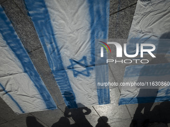 Iranian people stand next to Israeli flags that are prepared to set on fire during a gathering marking the memory of Lebanon's Hezbollah Sec...