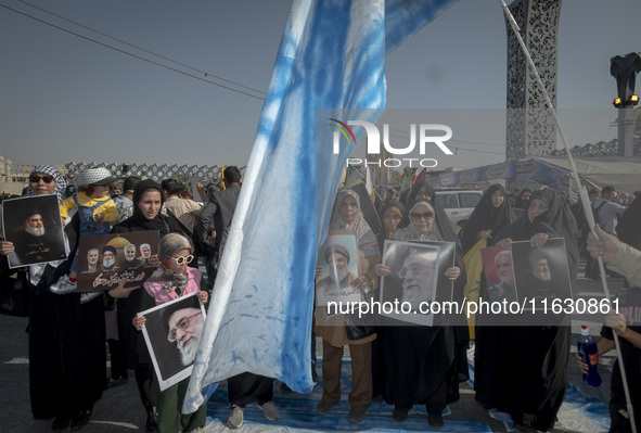 An Iranian man holds an Israeli flag while women and children hold portraits of Lebanon's Hezbollah Secretary General Hassan Nasrallah, form...