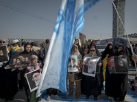 An Iranian man holds an Israeli flag while women and children hold portraits of Lebanon's Hezbollah Secretary General Hassan Nasrallah, form...