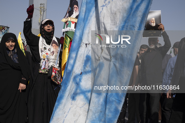 An Iranian man (not pictured) holds an Israeli flag while people hold portraits of Lebanon's Hezbollah Secretary General Hassan Nasrallah an...