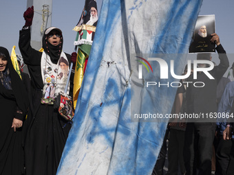 An Iranian man (not pictured) holds an Israeli flag while people hold portraits of Lebanon's Hezbollah Secretary General Hassan Nasrallah an...