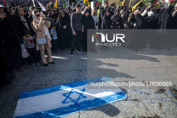 Veiled Iranian women stand next to an Israeli flag that is prepared to be set on fire during a gathering marking the memory of Lebanon's Hez...