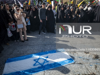 Veiled Iranian women stand next to an Israeli flag that is prepared to be set on fire during a gathering marking the memory of Lebanon's Hez...