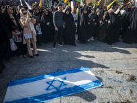 Veiled Iranian women stand next to an Israeli flag that is prepared to be set on fire during a gathering marking the memory of Lebanon's Hez...