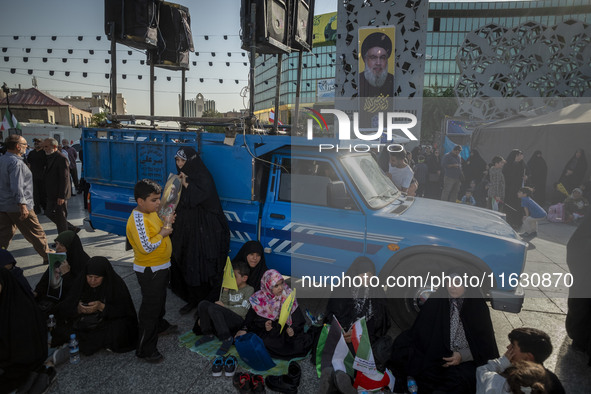 Veiled Iranian women sit under a portrait of Lebanon's Hezbollah Secretary General Hassan Nasrallah during a gathering marking the memory of...