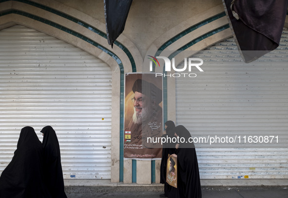 Veiled Iranian women walk past a portrait of Lebanon's Hezbollah Secretary General Hassan Nasrallah after a gathering marking the memory of...