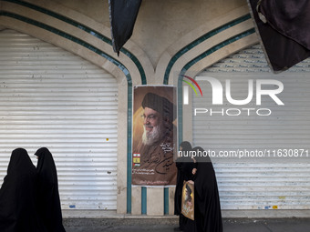 Veiled Iranian women walk past a portrait of Lebanon's Hezbollah Secretary General Hassan Nasrallah after a gathering marking the memory of...