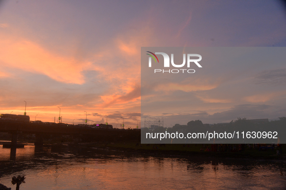 People and vehicles are seen as the sun sets in Siliguri, India, on October 2, 2024. 