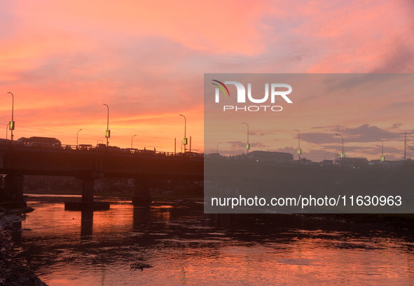 People and vehicles are seen as the sun sets in Siliguri, India, on October 2, 2024. 