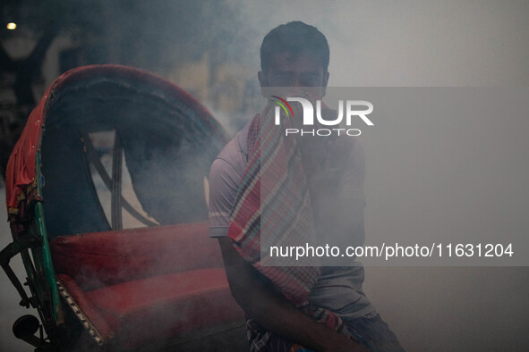 A man suffers in the smoke of mosquito repellent spray in Dhaka, Bangladesh, on October 2, 2024. 