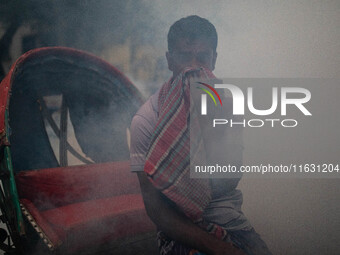 A man suffers in the smoke of mosquito repellent spray in Dhaka, Bangladesh, on October 2, 2024. (