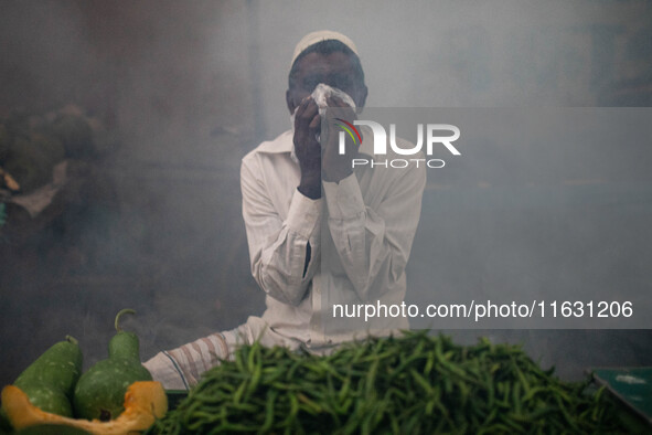 A man suffers in the smoke of mosquito repellent spray in Dhaka, Bangladesh, on October 2, 2024. 