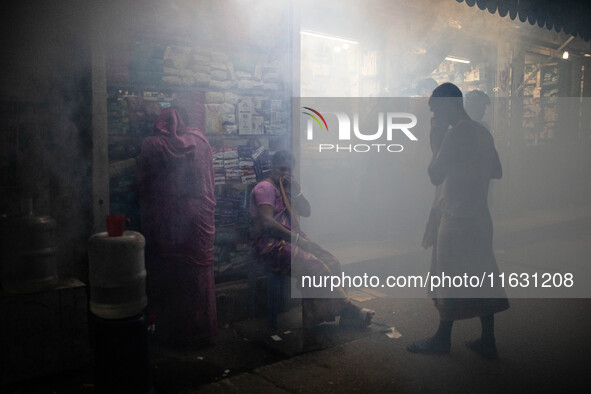 People suffer in the smoke of mosquito repellent spray in Dhaka, Bangladesh, on October 2, 2024. 