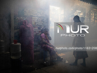 People suffer in the smoke of mosquito repellent spray in Dhaka, Bangladesh, on October 2, 2024. (