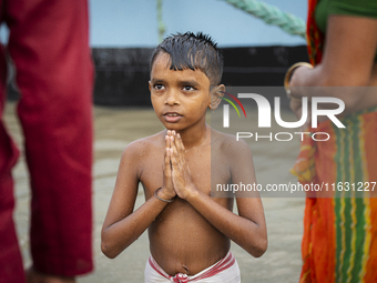 A child performs the 'Tarpan' ritual during Mahalaya prayers, also known as Pitru Paksha, at the Brahmaputra River in Guwahati, India, on Oc...