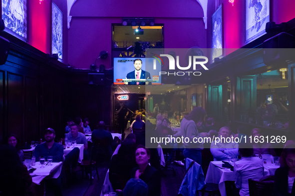 People watch the vice presidential debate under the pink and purple lights at Madhatter in Washington, DC, on October 1, 2024.  It was the o...