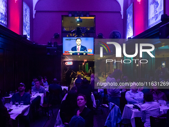 People watch the vice presidential debate under the pink and purple lights at Madhatter in Washington, DC, on October 1, 2024.  It was the o...