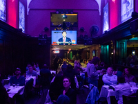 People watch the vice presidential debate under the pink and purple lights at Madhatter in Washington, DC, on October 1, 2024.  It was the o...