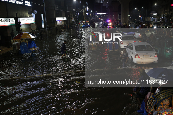 Residents make their way through a waterlogged street following heavy rainfall in Dhaka, Bangladesh, on October 2, 2024. Several roads in th...