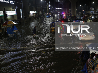 Residents make their way through a waterlogged street following heavy rainfall in Dhaka, Bangladesh, on October 2, 2024. Several roads in th...