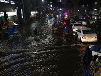 Residents make their way through a waterlogged street following heavy rainfall in Dhaka, Bangladesh, on October 2, 2024. Several roads in th...