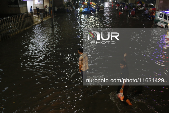 Residents walk through a waterlogged street following heavy rainfall in Dhaka, Bangladesh, on October 2, 2024. Several roads in the capital...