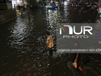 Residents walk through a waterlogged street following heavy rainfall in Dhaka, Bangladesh, on October 2, 2024. Several roads in the capital...