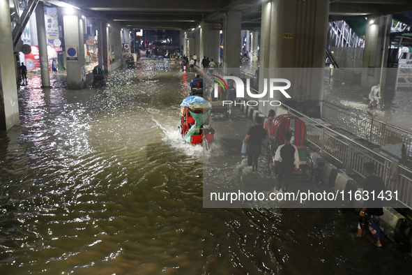 Residents make their way through a waterlogged street following heavy rainfall in Dhaka, Bangladesh, on October 2, 2024. Several roads in th...