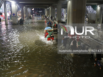 Residents make their way through a waterlogged street following heavy rainfall in Dhaka, Bangladesh, on October 2, 2024. Several roads in th...