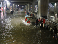 Residents make their way through a waterlogged street following heavy rainfall in Dhaka, Bangladesh, on October 2, 2024. Several roads in th...