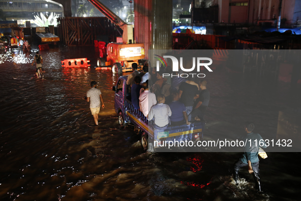 Residents make their way through a waterlogged street following heavy rainfall in Dhaka, Bangladesh, on October 2, 2024. Several roads in th...