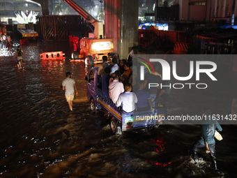 Residents make their way through a waterlogged street following heavy rainfall in Dhaka, Bangladesh, on October 2, 2024. Several roads in th...