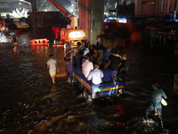 Residents make their way through a waterlogged street following heavy rainfall in Dhaka, Bangladesh, on October 2, 2024. Several roads in th...