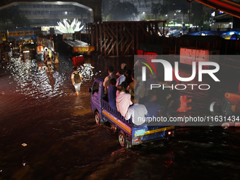 Residents make their way through a waterlogged street following heavy rainfall in Dhaka, Bangladesh, on October 2, 2024. Several roads in th...