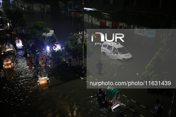 Residents make their way through a waterlogged street following heavy rainfall in Dhaka, Bangladesh, on October 2, 2024. Several roads in th...