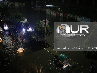 Residents make their way through a waterlogged street following heavy rainfall in Dhaka, Bangladesh, on October 2, 2024. Several roads in th...