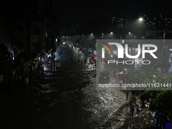 Residents make their way through a waterlogged street following heavy rainfall in Dhaka, Bangladesh, on October 2, 2024. Several roads in th...