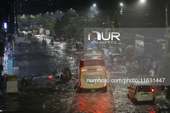 Residents make their way through a waterlogged street following heavy rainfall in Dhaka, Bangladesh, on October 2, 2024. Several roads in th...