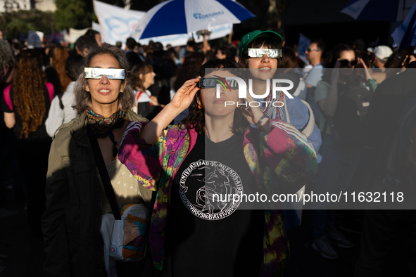 People watch an annular solar eclipse during a protest against Argentina's President Javier Milei's promise to veto a law to finance univers...