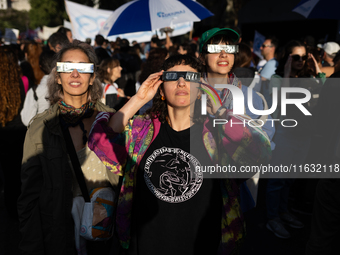 People watch an annular solar eclipse during a protest against Argentina's President Javier Milei's promise to veto a law to finance univers...