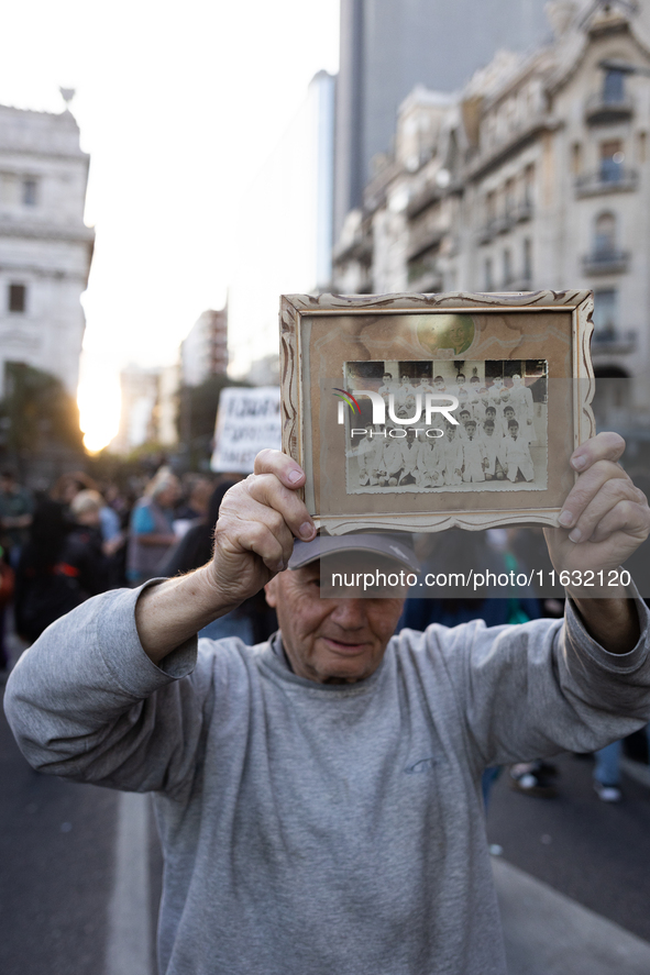 A man holds a photo of his primary class at a public school during a protest against Argentina's President Javier Milei's promise to veto a...