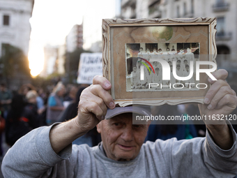 A man holds a photo of his primary class at a public school during a protest against Argentina's President Javier Milei's promise to veto a...