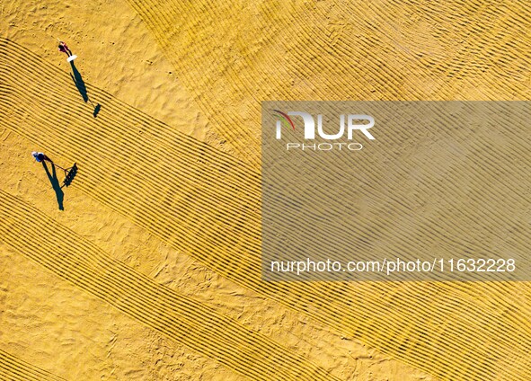 A worker dries rice at a sun-drying farm in Suqian, Jiangsu province, China, on October 2, 2024. 