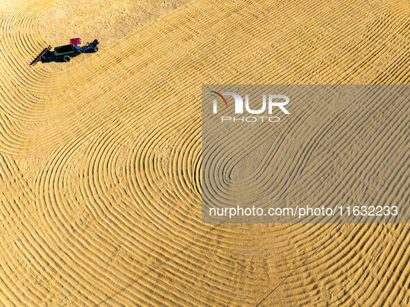 A worker dries rice at a sun-drying farm in Suqian, Jiangsu province, China, on October 2, 2024. 