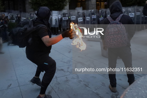 Members of the Anarchist Black Bloc throw Molotov cocktails at the police during the march to mark the 56th anniversary of the Tlatelolco Ma...