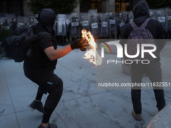 Members of the Anarchist Black Bloc throw Molotov cocktails at the police during the march to mark the 56th anniversary of the Tlatelolco Ma...