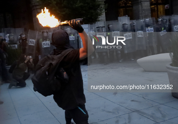 Members of the Anarchist Black Bloc throw Molotov cocktails at the police during the march to mark the 56th anniversary of the Tlatelolco Ma...