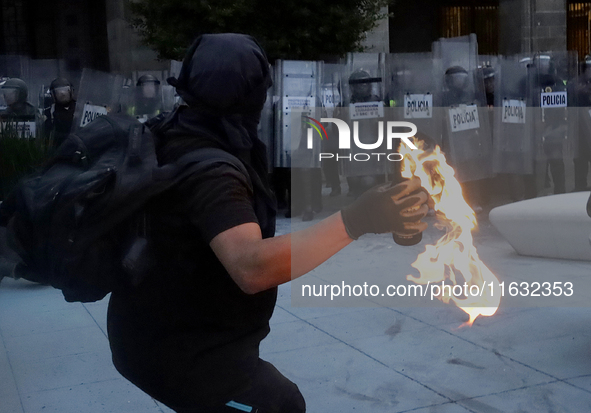 Members of the Anarchist Black Bloc throw Molotov cocktails at the police during the march to mark the 56th anniversary of the Tlatelolco Ma...