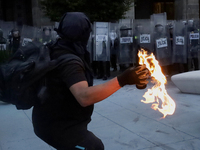 Members of the Anarchist Black Bloc throw Molotov cocktails at the police during the march to mark the 56th anniversary of the Tlatelolco Ma...