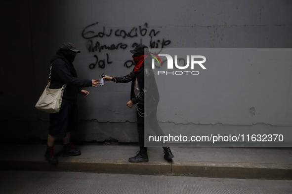 Members of the Anarchist Black Bloc paint graffiti during the march to mark the 56th anniversary of the Tlatelolco Massacre that occurred on...